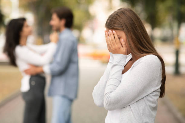 Upset woman crying, seeing her boyfriend with other girl in park