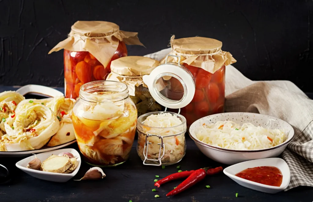 cabbage kimchi tomatoes marinated sauerkraut sour glass jars rustic kitchen table.jpg